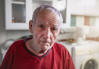 Wall Mural - Portrait of old man sitting in kitchen