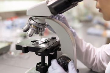 Sticker - Close-up of female scientist examining samples through the microscope in the laboratory