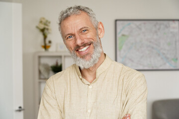 Smiling relaxed mature older bearded hipster man looking at camera. Happy handsome confident middle aged 50s male professional, standing at home office posing indoors for close up headshot portrait.