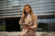 Young business woman using her mobile cell phone while holding a tablet