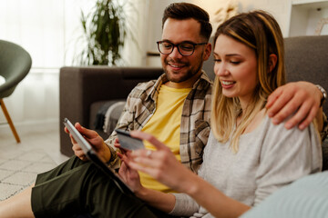 Wall Mural - Image of excited cheery young loving couple at home on floor near sofa using laptop computer.