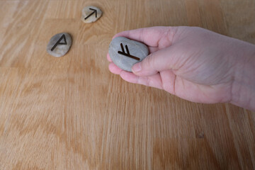 fortuneteller's hand explains the meaning of the Scandinavian, Slavic runes on flat stones for fortune-telling for the future, the concept of magic and isoterics