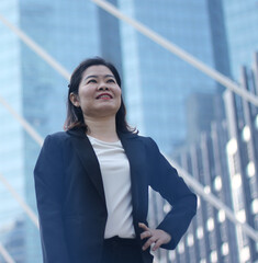 Asian 40s business woman smiling posing in modern office. Successful Business people walking on city street. Selective Focus
