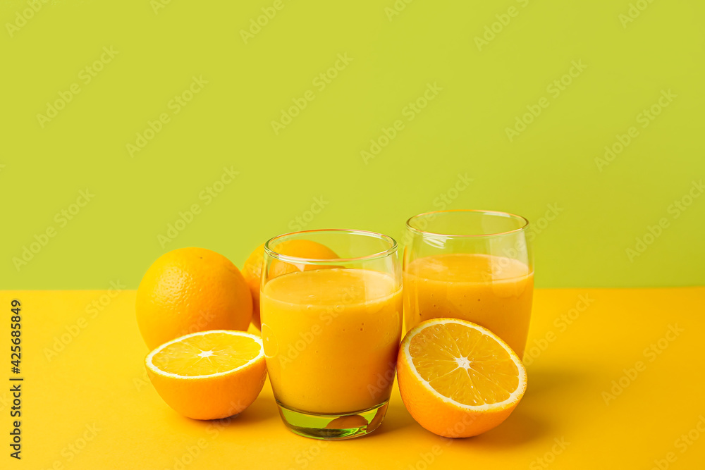 Glasses of orange smoothie on color background