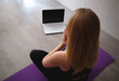 © Aleksandra Iarosh - young woman doing asana at home on yoga mat in front of laptop