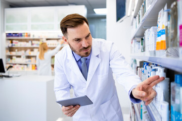 Wall Mural - Pharmacist counting medicines and checking supply on tablet computer in pharmacy store.