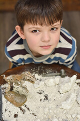 Happy child digging the dinosaur and having fun with archaeology excavation kit. Boy plays an archaeologist excavated, training for dig fossil