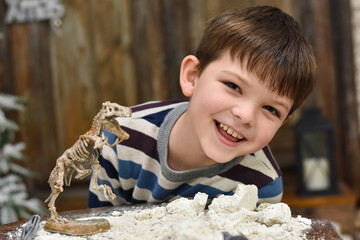 Happy child digging the dinosaur and having fun with archaeology excavation kit. Boy plays an archaeologist excavated, training for dig fossil