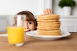 © Lisa Tichané - Toddler peeking behind kitchen table stealing a pancake
