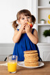 © Lisa Tichané - Toddler girl standing on kitchen chair eating apple