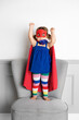 © Lisa Tichané - Funny toddler girl dressed as superhero standing on chair