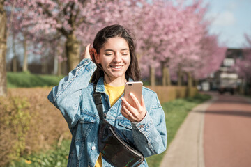 cheerful mixed races woman using phone on the street for a video call or order online