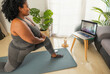 Young African woman doing pilates virtual fitness class with laptop at home - Sport wellness people lifestyle concept