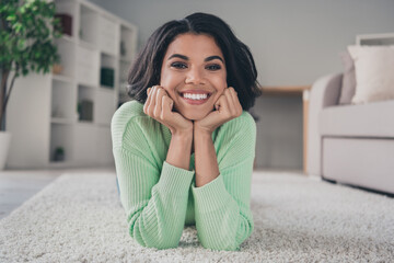 Canvas Print - Photo of young attractive cheerful african woman happy positive smile lie on the floor hands touch cheeks indoors