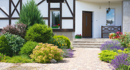 Wall Mural - A corner of the garden in front of the house. Garden design. Beautiful landscape with garden corner. Blooming flowers background