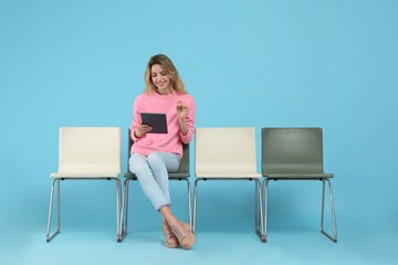 Poster - Young woman with tablet waiting for job interview on light blue background