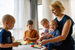 © NDABCREATIVITY - Mother or nursery teacher teaches her children to work with colorful play clay toys
