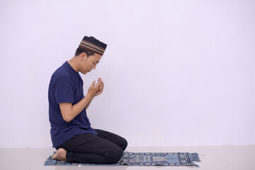 young asian muslim praying to the God isolated white background