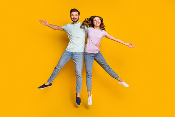 Sticker - Full length body size view of attractive cheerful couple jumping hugging having fun isolated over bright yellow color background