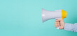 © nisara - Male Hand is hold megaphone and wear blue shirt on green or mint or Tiffany Blue background.