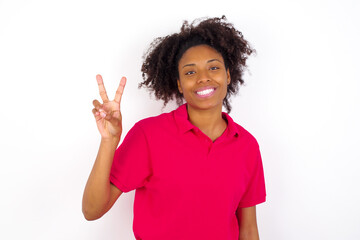 Wall Mural - young beautiful African American woman wearing pink t-shirt against white wall showing and pointing up with fingers number two while smiling confident and happy.