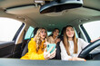 © F8  \ Suport Ukraine - Three happy girlfriends go on a trip. Three women ride in the car, look at the phone to fing corect direction.