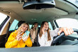 © F8  \ Suport Ukraine - Three best friends women in the car and uses smart phones while drive car in road trip