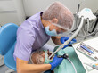 The dentist in an inconvenient position with the help of specialized instruments treats the patient's oral cavity.