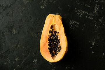 Wall Mural - Sliced fresh and tasty papaya on a black textured background. Tropical fruit. Copy space