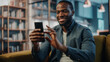 © Gorodenkoff - Excited Black African American Man Using Smartphone while Resting on a Sofa in Living Room. Happy Man Smiling at Home and Chatting to Colleagues and Clients Over the Internet. Using Social Networks.
