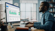 © Gorodenkoff - Handsome Black African American Specialist Working on Desktop Computer in Creative Home Living Room. Freelance Male is Doing Market Analysis and Creates Report with Charts for Clients and Employer.