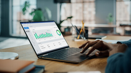 Close Up on Hands of Black African American Working on Desktop Computer in Creative Home Living Room. Freelance Male is Doing Market Analysis and Creates Report with Charts for Clients and Employer.