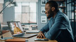 © Gorodenkoff - Handsome African American Man Having a Video Call on Laptop Computer while Sitting Behind Desk in Living Room. Freelancer Working From Home and Talking to Colleagues and Clients Over the Internet.