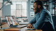 © Gorodenkoff - Handsome African American Man Having a Video Call on Laptop Computer while Sitting Behind Desk in Living Room. Freelancer Working From Home and Talking to Colleagues and Clients Over the Internet.