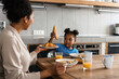 © Drobot Dean - Happy black mother and daughter having breakfast at home kitchen