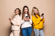 © F8  \ Suport Ukraine - Three attractive women using phones isolated on beige background