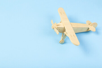 Model of a wooden toy plane, airliner, on a blue background. the concept of travel and transport and children's fantasies