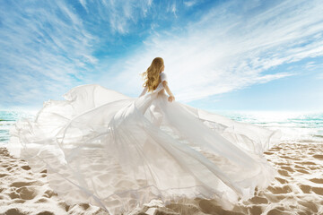 Woman on Beach in White Dress flying on Wind. Summer Vacation. Beach Sand Sea Sunshine Sky