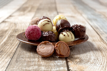 Chocolates candy on a plate on a wooden table. Cutaway candy, two halves. Close-up. High quality photo