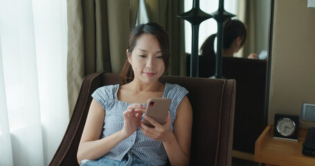 Wall Mural - Woman use of smart phone and sit on sofa