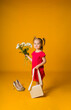 little girl in a red dress with a beige handbag holds a bouquet of white flowers on a yellow background with space for text