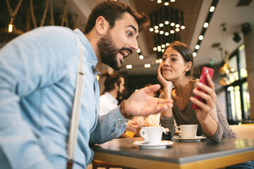 Sticker - Young happy couple using smartphone in cafe