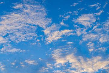 Blue sunny sky with white contrasting clouds for background