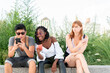© Spectral-Design - Friends checking mobile phones sitting in a park