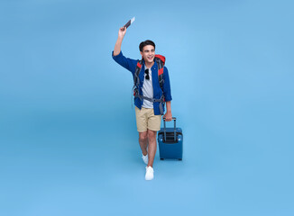 Happy smiling Asian bag packer man with passport and luggage enjoying their summer vacation getaway in blue background.