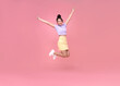 © NaMong Productions - Happy Asian woman smiling and jumping while celebrating success isolated over pink background.