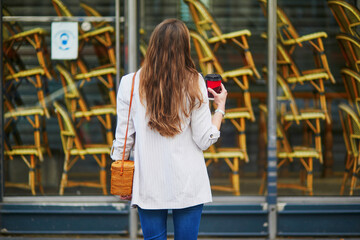 Young girl standing near closed restaurant in Paris and wearing protective face mask during coronavirus outbreak