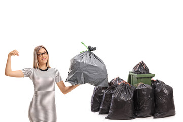 Sticker - Young woman showing biceps and holding a garbage bag in front of a bin