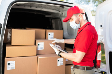 Wall Mural - Male courier using a tablet while unloading a delivery truck