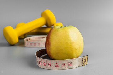 Gym and workout, Healthy lifestyle concept foto. Flat lay of sport. Athlete's set with centimeter tape, green apple and dumbbells on a grey background with space for text